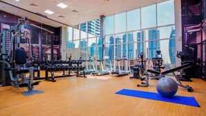 A gym with exercise equipment, large windows, and a city view.