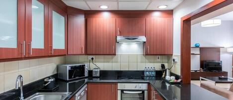 A modern kitchen with wooden cabinets, stainless steel appliances, and a black countertop.