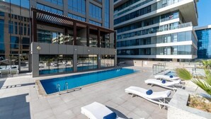 Un área de piscina en la azotea con sillones de descanso y una pérgola.