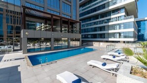 En pool på taket med solstolar och en pergola.