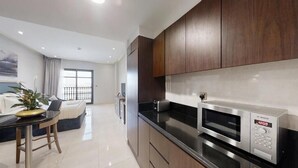 A modern kitchen with dark wooden cabinets, a black countertop, and a Bosch microwave.