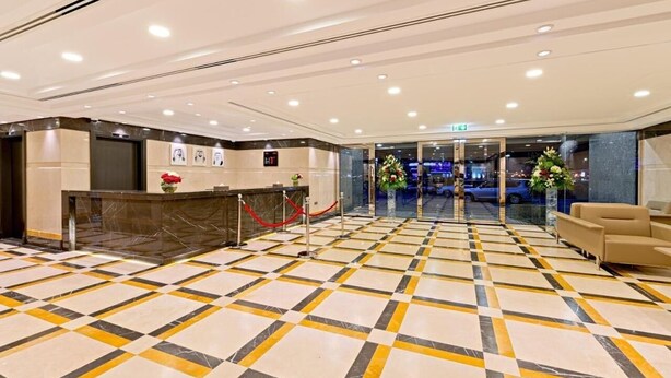Een hotel lobby met een receptiebalie, een zitgedeelte en een incheckplein.