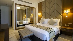 A hotel room with a large bed, a bench, a mirror, and a wall with geometric patterns. - One Bedroom Apartment in Al Qusais By E R (Dubai)