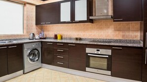 Una cucina moderna con mobili scuri, una lavatrice integrata e un forno in acciaio inossidabile.