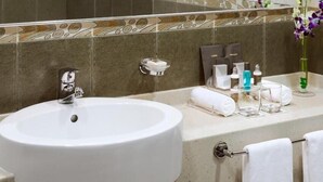 Et badeværelse med en hvid vask, et håndklædestativ og toiletartikler på bordet.