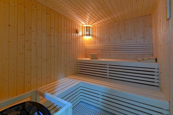 A sauna with wooden walls and benches, a bench with a towel, and a small table with a towel.
