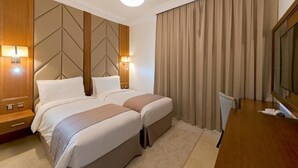 Een hotelkamer met twee bedden, een televisie en een groot raam met gordijnen.