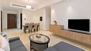 Een moderne woonkamer met een flatscreen televisie, een glazen salontafel en een bank.