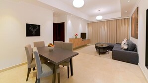 A modern living room with a dining area, a sofa, and a TV. - One Bedroom Apartment Near Fujairah Mall (Fujairah)