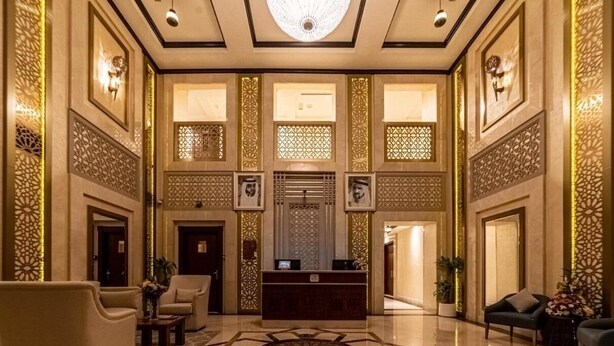 A spacious lobby with a reception desk, seating areas, and decorative wall panels. - One Bedroom Apartment In Jaddaf By E R (Dubai)