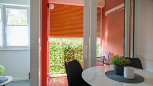 Ein Essbereich mit einem runden Tisch, Stühlen, einer Topfpflanze und einem Fenster mit Jalousien.