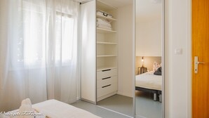 Ein Schlafzimmer mit einem Bett, einem Schrank mit Regalen und einer Holztür.