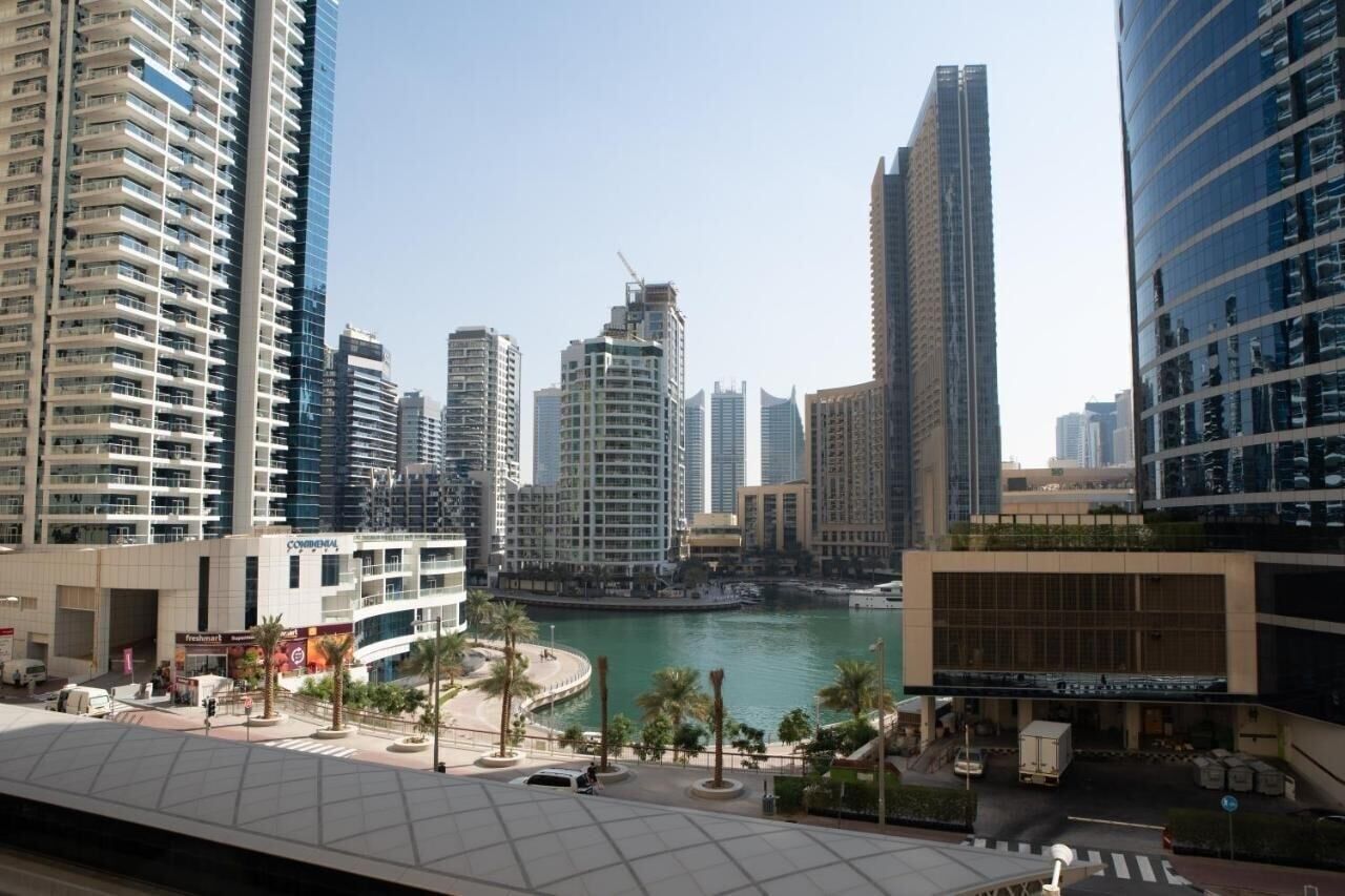 A modern urban area with high-rise buildings, a waterfront, and a commercial building with a large glass facade.