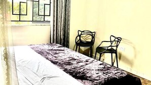 A room with a bed, a window with a view, a chair, and curtains. - Apartment - Sleeps 2 - Parking - Garden (Kampala)