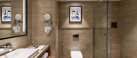 A modern bathroom with a large mirror, a sink, a toilet, and a glass-enclosed shower.
