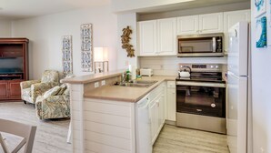 A compact kitchen with white cabinets, a built-in microwave, and an oven. - Balcony & Beach Access: Oceanfront PCB Condo (Panama City)