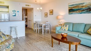 A modern living room with a sofa, a coffee table, and a dining area with chairs and a table. - Balcony & Beach Access: Oceanfront PCB Condo (Panama City)
