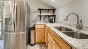 A kitchen with a stainless steel refrigerator, wooden cabinets, a granite countertop, a double sink, and a coffee machine. - Young Harris Vacation Rental w/ Mountain Views! (Young Harris)