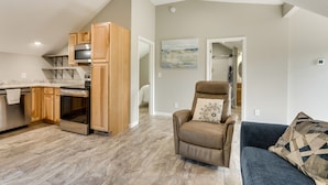 A modern kitchen with wooden cabinets and stainless steel appliances, a leather recliner, and a blue sofa with patterned cushions. - Young Harris Vacation Rental w/ Mountain Views! (Young Harris)
