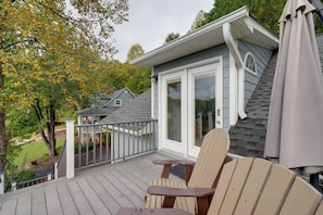 A deck with a chair and umbrella, overlooking a house with a covered porch and a garage. - Young Harris Vacation Rental w/ Mountain Views! (Young Harris)