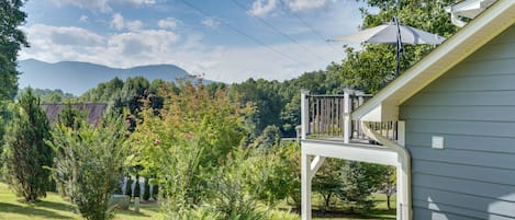 A residential property with a covered porch, a landscaped garden, and a view of mountains in the background.