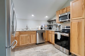 A modern kitchen with wooden cabinets, stainless steel appliances, and a tiled floor. - Young Harris Vacation Rental w/ Mountain Views! (Young Harris)