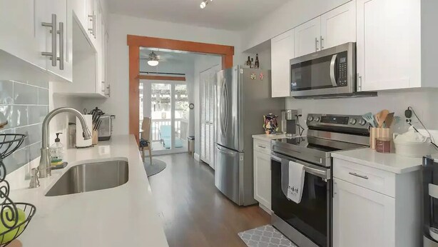 A modern kitchen with stainless steel appliances, white cabinetry, and a large island with a sink. - La Casita Solar II (Clearwater)
