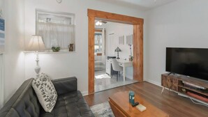A living room with a dark leather sofa, a wooden coffee table, a flat-screen TV, and a ceiling fan. - La Casita Solar II (Clearwater)
