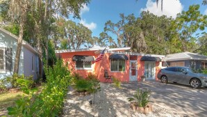 A single-story house with a red exterior, a driveway, and a parked car. - La Casita Solar II (Clearwater)