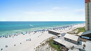 A beach with a high-rise building in the background. - Sunbird Beach Resort by Book That Condo (Panama City Beach)