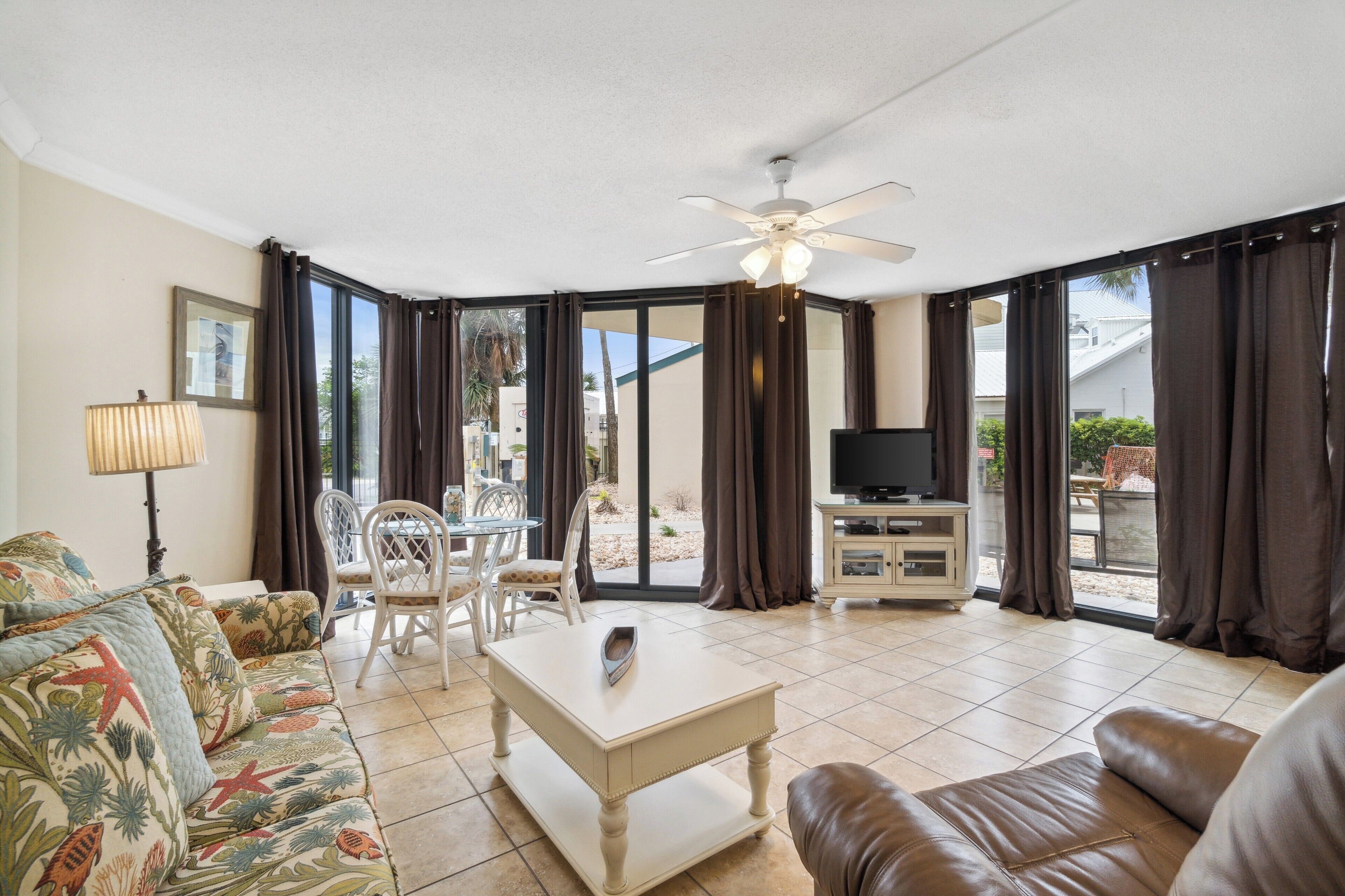 A living room with a sofa, a coffee table, a TV stand, and a ceiling fan.