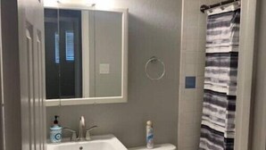 A bathroom with a white sink, mirror, and toilet. There is a striped shower curtain and a towel rack. - Cozy 3bd. 2bth home, Panoramic views, near UNR, DT, FRWY & RENO AIRPORT. (Reno)