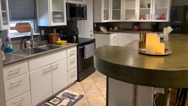 A kitchen with white cabinets, a microwave, a stove, and a sink. - Cozy 3bd. 2bth home, Panoramic views, near UNR, DT, FRWY & RENO AIRPORT. (Reno)