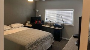 A bedroom with a bed, a desk, a chair, a ceiling fan, a window with blinds, and a lamp. - Cozy 3bd. 2bth home, Panoramic views, near UNR, DT, FRWY & RENO AIRPORT. (Reno)