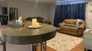 A modern living room with a round dining table, a sofa, a coffee table, and a patterned rug. - Cozy 3bd. 2bth home, Panoramic views, near UNR, DT, FRWY & RENO AIRPORT. (Reno)