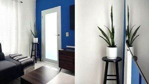 Una sala moderna con un sofá oscuro, una mesa de centro, una mesita auxiliar con una planta y una pared azul de acento.