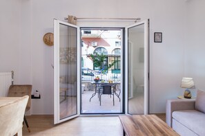 Ein modernes Wohnzimmer mit einer Schiebetür zu einer Außenpatio. Das Zimmer verfügt über einen Holztisch, ein Sofa und einen Sessel.