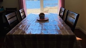 A dining table with a plaid tablecloth, four chairs, and a central table lamp.