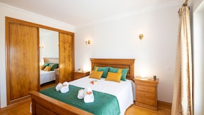 A hotel room with a wooden bed, green and yellow pillows, a large mirror, and a wooden nightstand. - Retreat w/ Heatable Pool and BBQ in Galé (Galé)