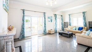 A spacious living room with a marble fireplace, a sofa set, a coffee table, and a dining area with a glass door leading outside. - Retreat w/ Heatable Pool and BBQ in Galé (Galé)