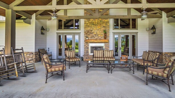 A covered patio area with stone walls, a fireplace, and outdoor furniture.
