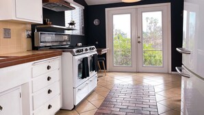 A kitchen with white cabinets, a stove, a microwave, and a brick-patterned floor.