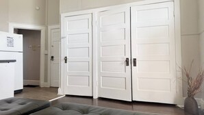 Een modern interieur met een grijze gestuufde bank, witte dubbele deuren en een koelkast met een QR-code.