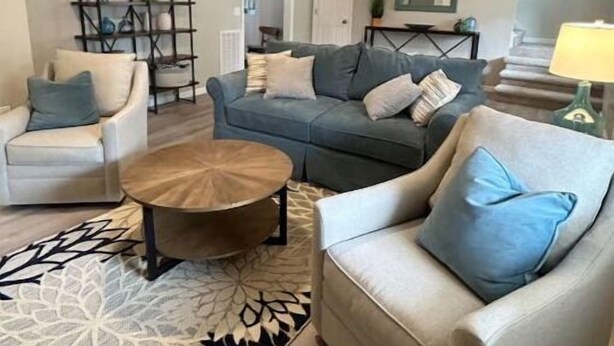 A living room with a sofa, armchairs, a coffee table, a bookshelf, and ceiling fans. - Lakeside on Greenwood (Muskegon)