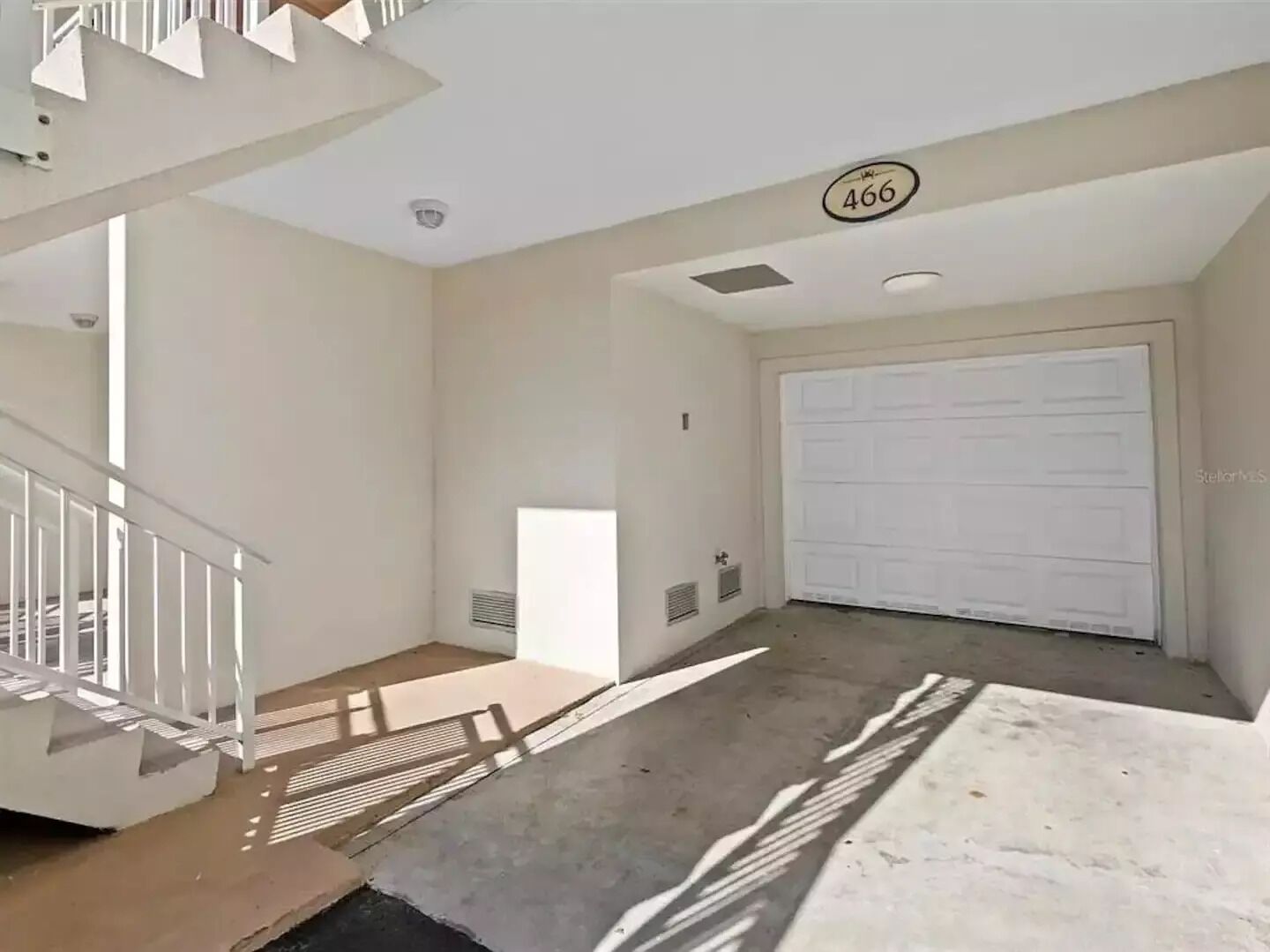 Un intérieur spacieux avec une grande porte de garage, un escalier et le numéro 466 inscrit au plafond.