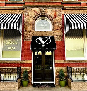 A building with a black awning displaying the number 211 and a logo.