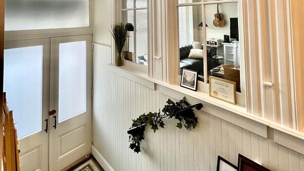 A staircase with a view to a living area, a ceiling fan, and a window with a view of the outside.
