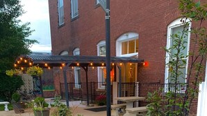 A courtyard with a brick building, outdoor seating, and a variety of plants and flowers.