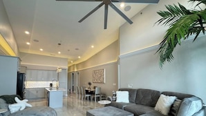 A modern living room with a grey sofa, ottomans, and a starfish decoration. There is a dining area in the background with a table and chairs. - Topsider Penthouse 511 with Resort Pools (Osage Beach)
