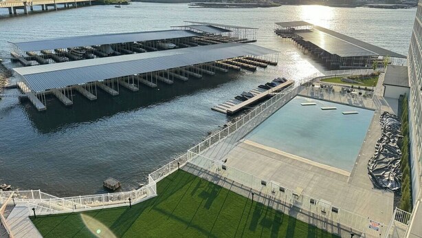An aerial view of a waterfront property with a large open plaza, a covered swimming area, and a dock extending into the water. - Topsider Penthouse 511 with Resort Pools (Osage Beach)